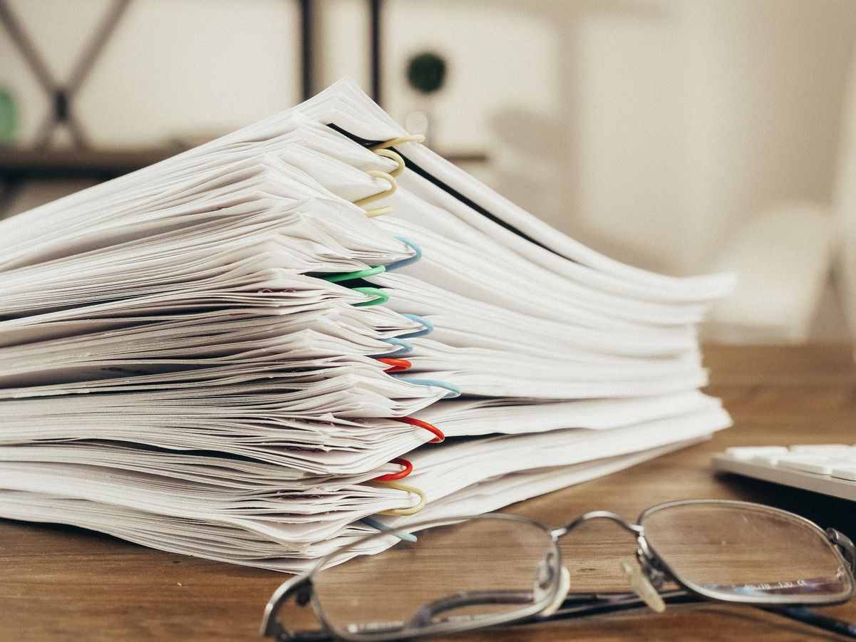 A tall stack of clipped reports and filings on a desk