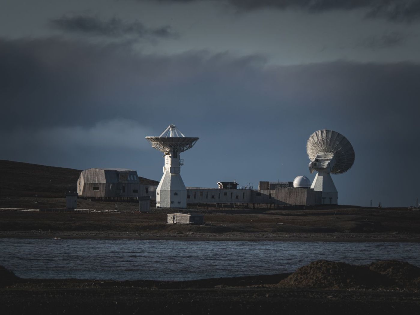 A radar and satellite tracking station under a stormy sky