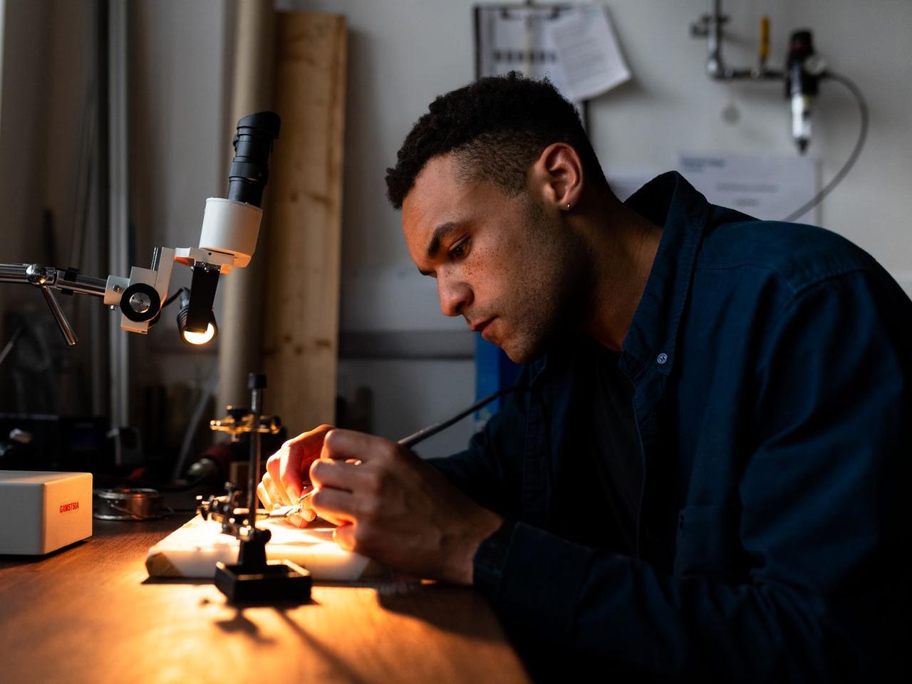 An engineer assembling a prototype at a lit workbench