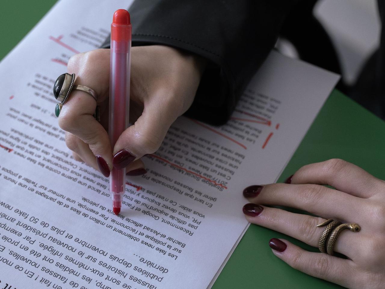 A reviewer marking up a printed document with a red pen